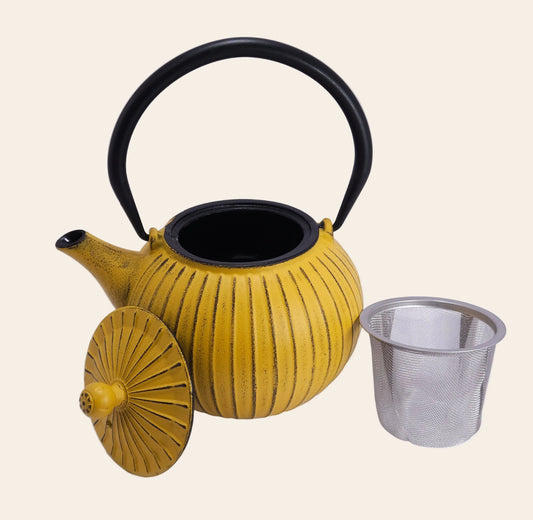 Petite théière jaune en fonte ouverte avec son panier d'infusion en acier inoxydable et intérieur émaillé noir.